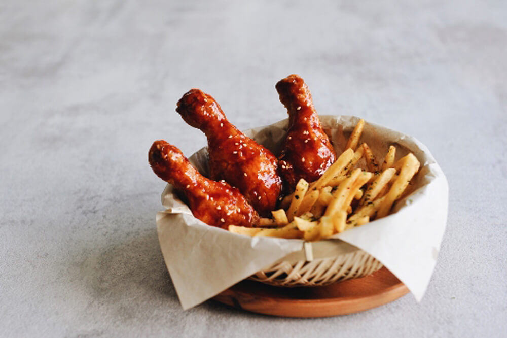 A basket of korean fried chicken and fries displayed on a table